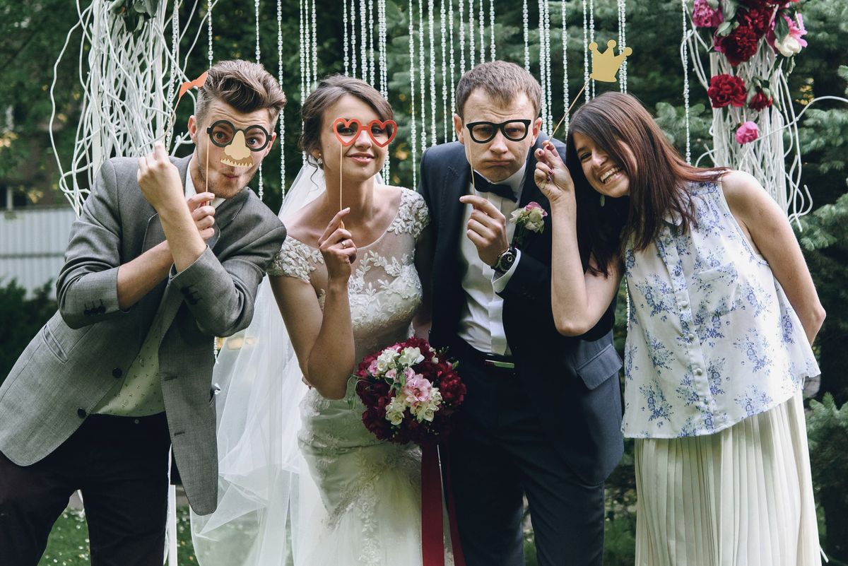 Bride, groom, and guests posing with photo booth props at a Fort Worth wedding